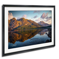 a serene mountain landscape with a calm lake reflecting the surrounding mountains and the sky.