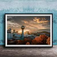 a city skyline at sunset, with a large tower in the center and a colorful sky in the background.