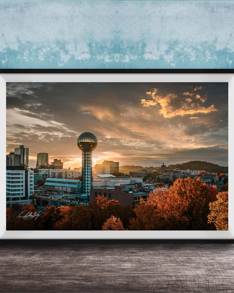 a city skyline at sunset, with a large tower in the center and a colorful sky in the background.