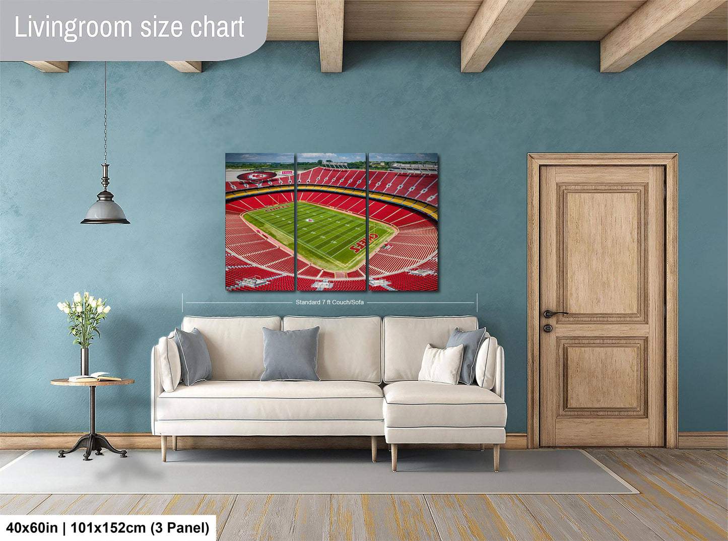 The image is a living room with a large wall-mounted painting depicting a football stadium. The painting is divided into three panels, with the top and bottom panels showing the stadium and the middle panel showing the field. The painting is framed in a wooden frame and hangs above a white sofa.