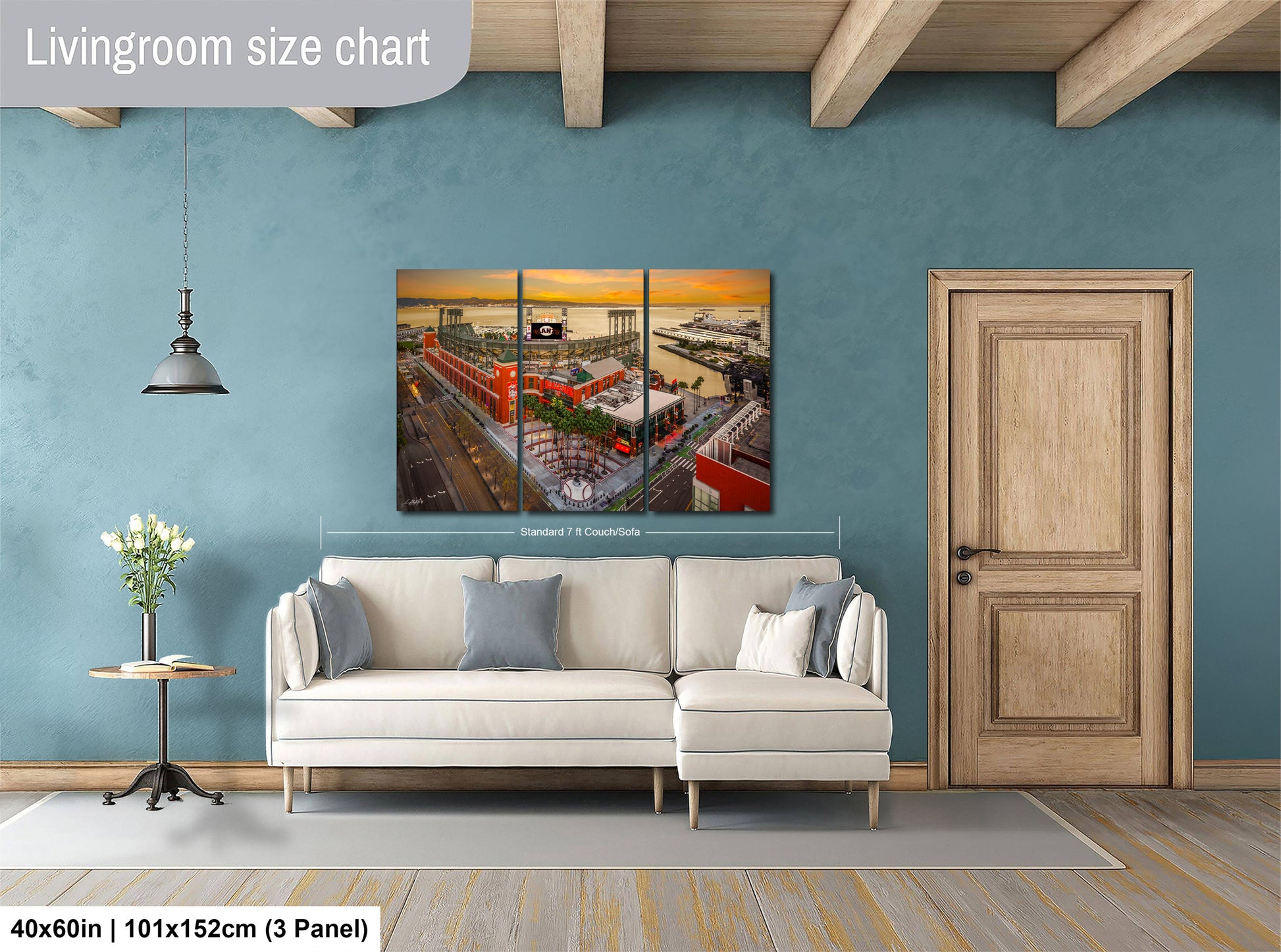 The image is a living room with a large white sofa, a wooden door, and a painting of a cityscape hanging on the wall.