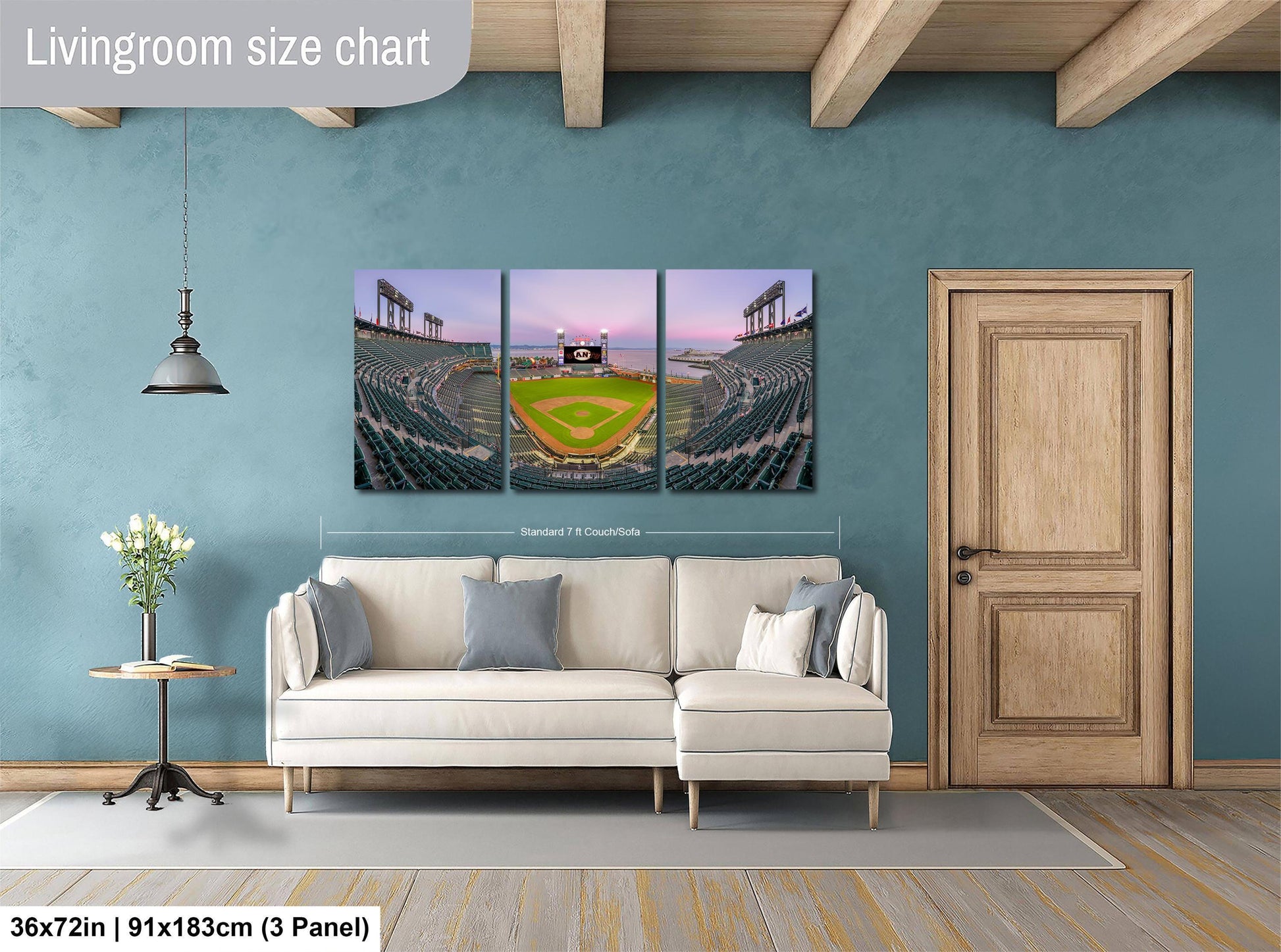 The image is a living room with a large wall art depicting a baseball stadium. The wall art is a collage of three panels, each showing different aspects of the stadium, including the field, seating, and the sky. The living room has a white sofa and a wooden door, creating a cozy and inviting atmosphere.