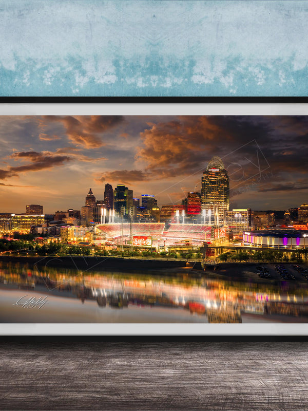 a city skyline at night, with the buildings illuminated and their reflections visible in the water below.