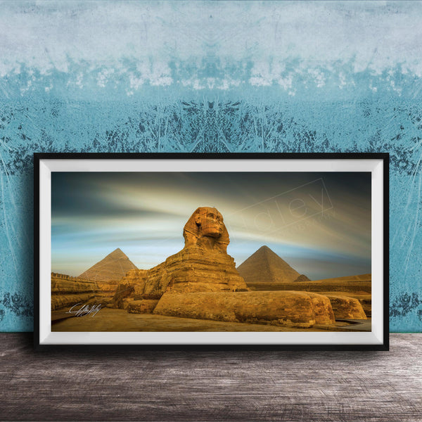 a framed photograph of the Great Sphinx of Giza, a large limestone statue of a mythical creature, in front of the pyramids of Giza in Egypt.