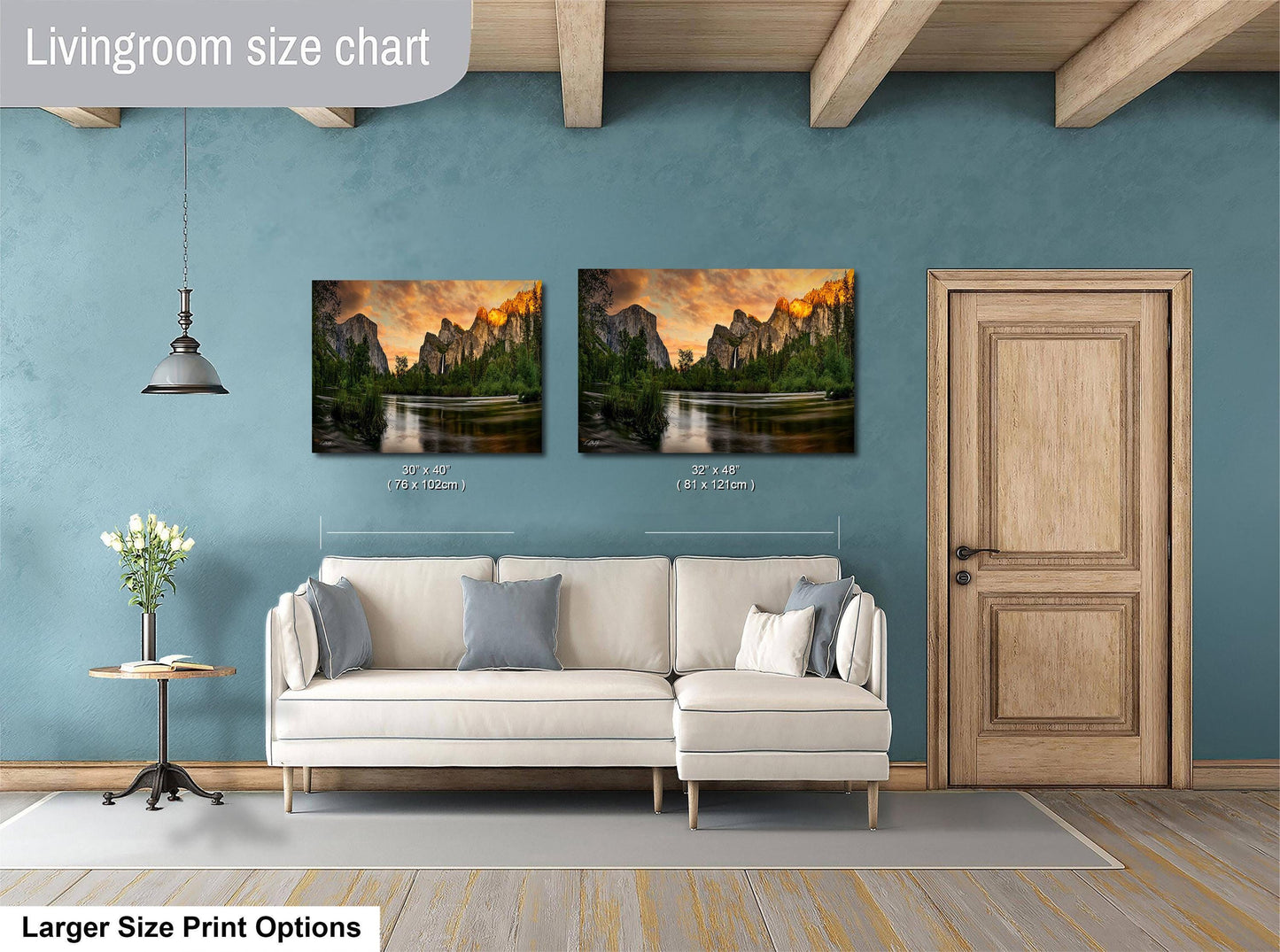 a living room with a white sofa and a wooden door. Above the sofa, there are two framed landscape paintings depicting a scenic mountain view. The paintings are of similar size, with one being larger than the other. The living room has a blue wall and a wooden ceiling, creating a cozy and inviting atmosphere.