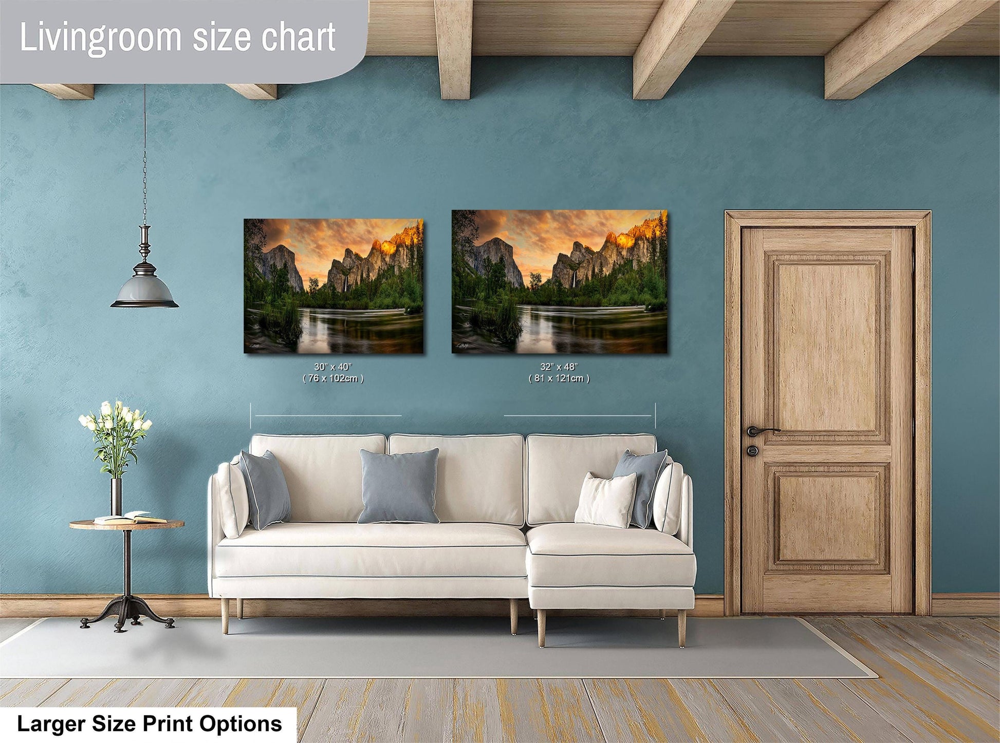 a living room with a white sofa and a wooden door. Above the sofa, there are two framed landscape paintings depicting a scenic mountain view. The paintings are of similar size, with one being larger than the other. The living room has a blue wall and a wooden ceiling, creating a cozy and inviting atmosphere.