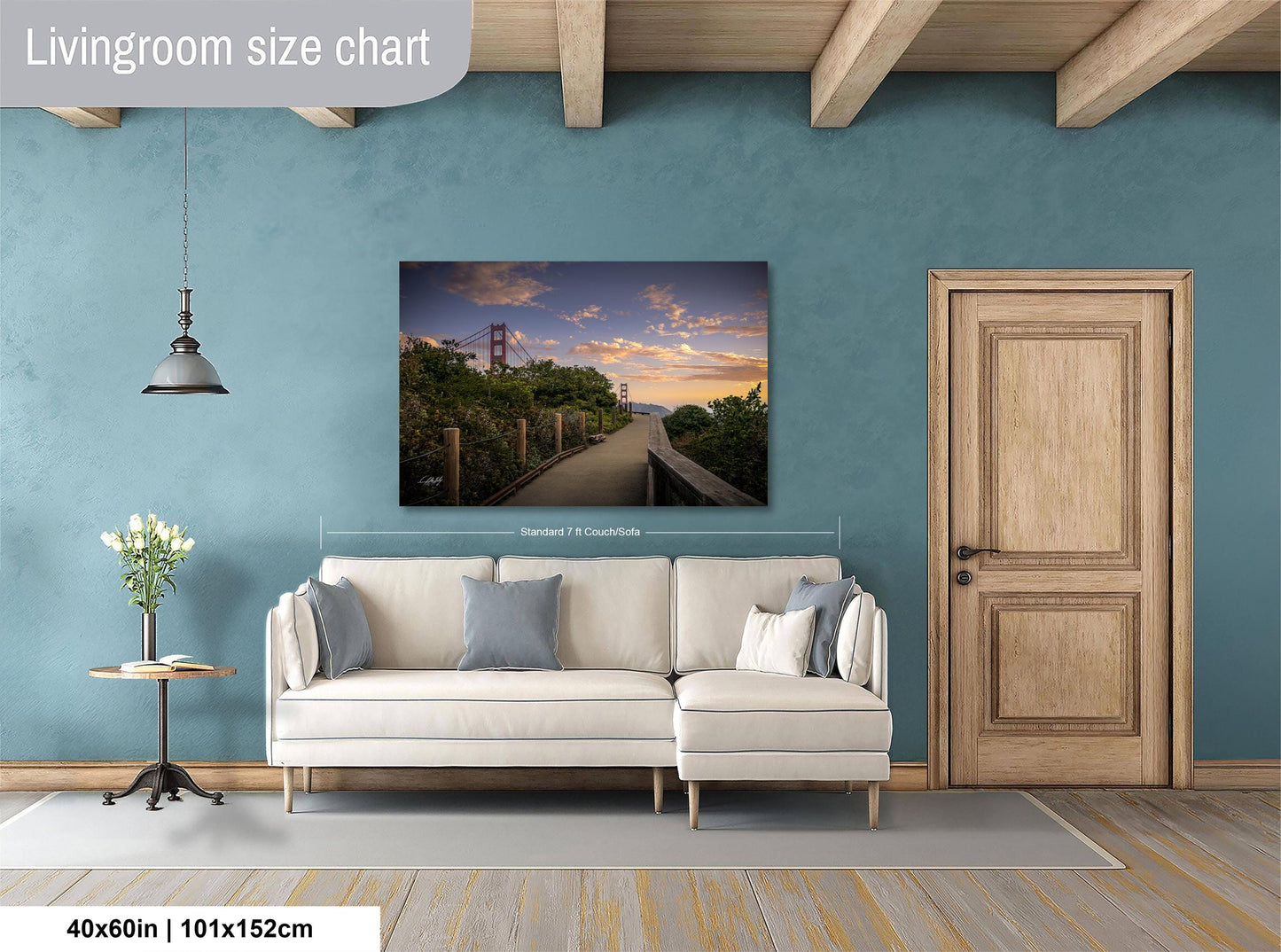 a living room with a large painting of a bridge in the background, a white sofa, a wooden door, and a small table with a vase of flowers.