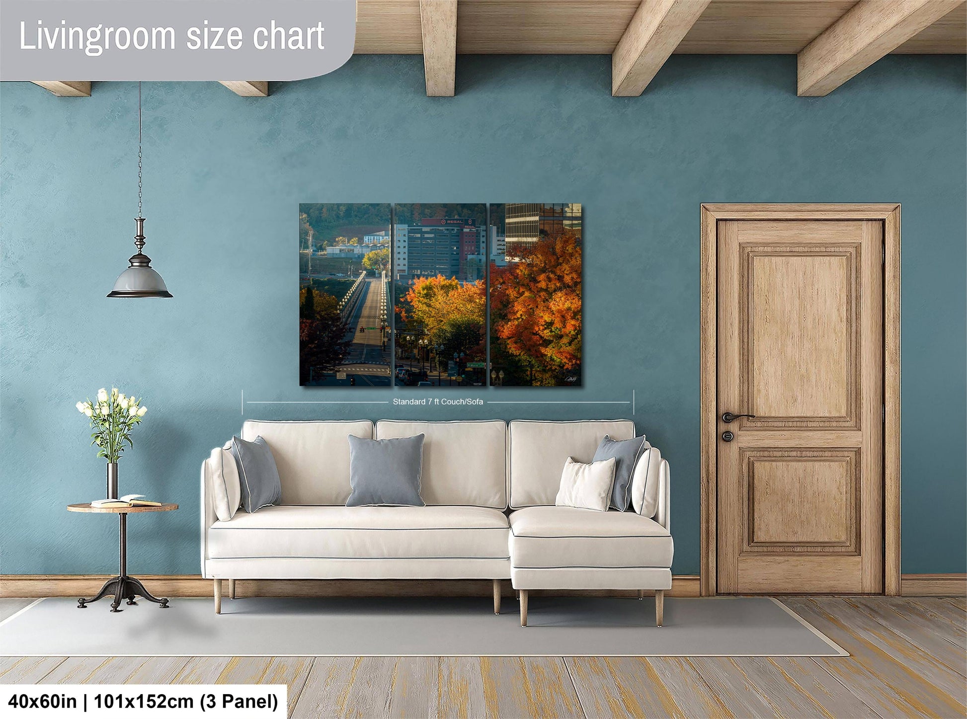 The image is a living room with a large white sofa, a wooden door, and a painting of a cityscape hanging on the wall.