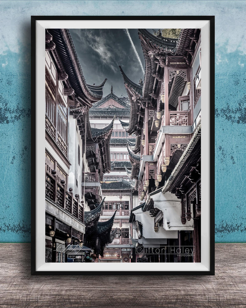 A framed photograph of a traditional Chinese street lined with ornate buildings and pagodas, set against a blue textured background.