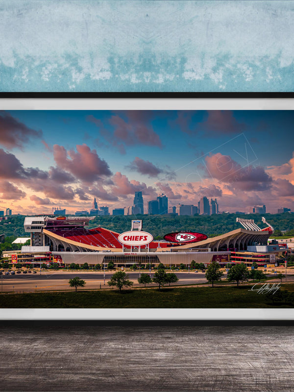 A framed photograph of the Kansas City Chiefs football stadium, with the city skyline in the background.