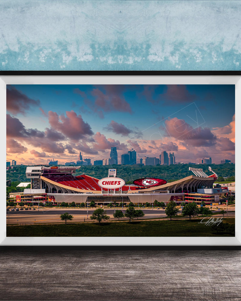 A framed photograph of the Kansas City Chiefs football stadium, with the city skyline in the background.