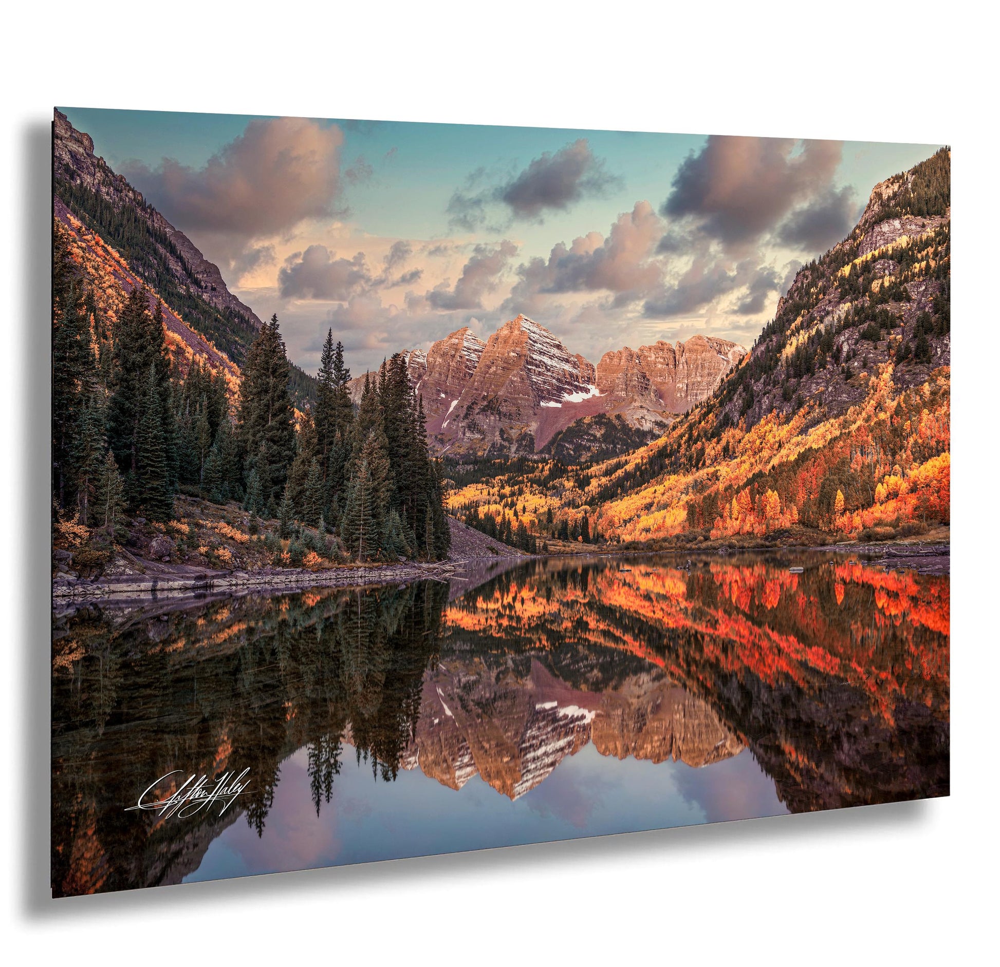 a serene mountain landscape with a lake reflecting the vibrant colors of the autumn foliage. The mountains are adorned with a mix of green and brown, creating a beautiful contrast against the clear blue sky. The lake is surrounded by trees with orange and yellow leaves, adding a warm and cozy atmosphere to the scene. The image is a captivating representation of nature's beauty and the tranquility of the mountains.