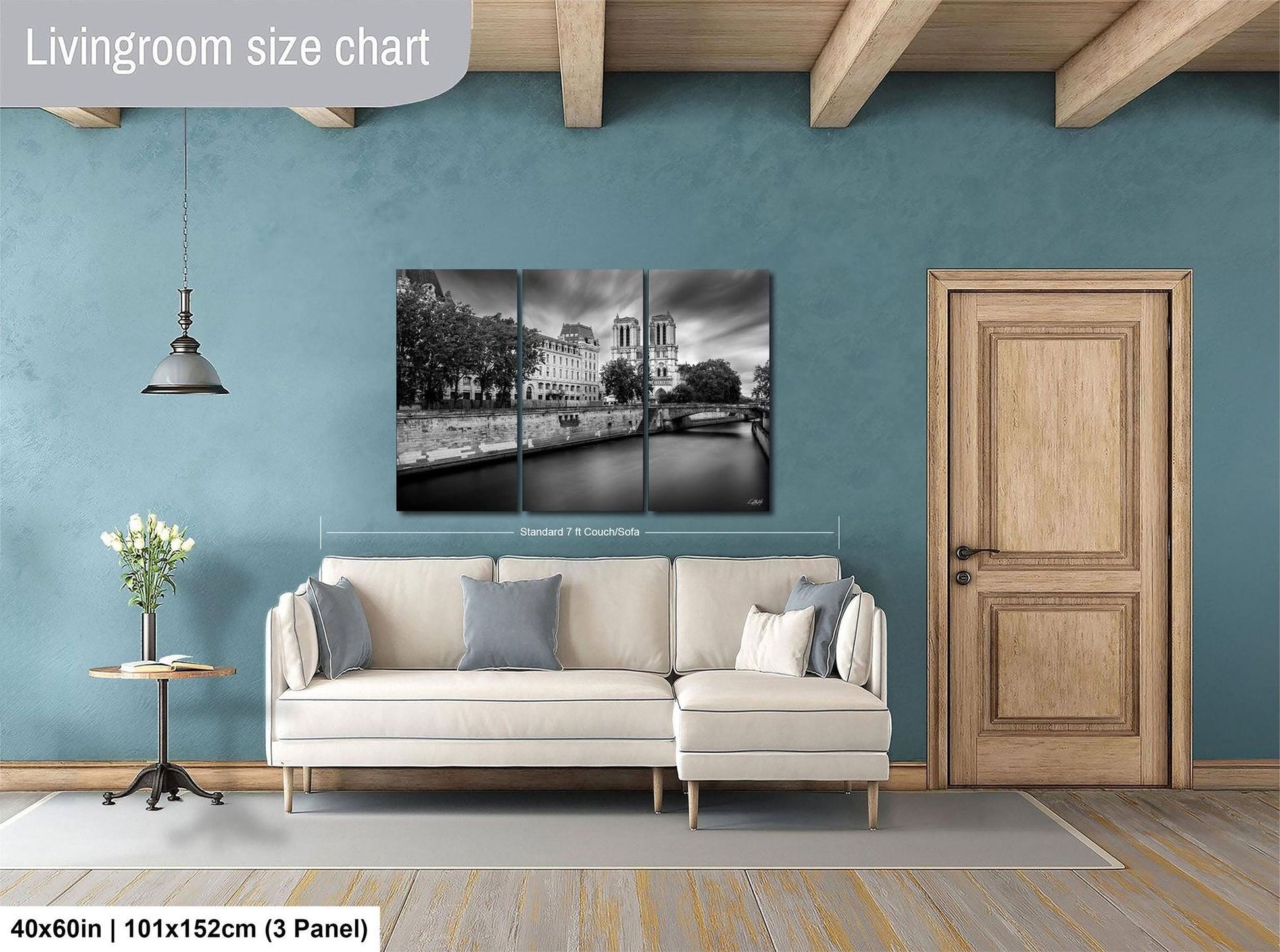 The image is a living room with a large white sofa, a wooden door, and a wall with a black and white photograph of a cityscape.