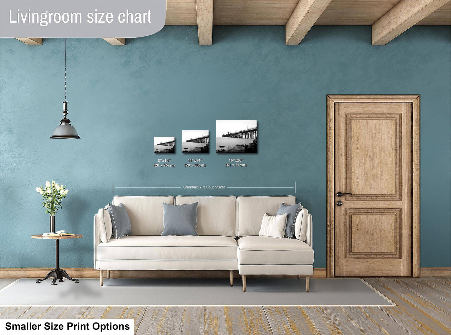 The image is a living room with a white sofa, a wooden door, and a hanging light fixture. There are three framed pictures of landscapes displayed on the wall above the sofa.