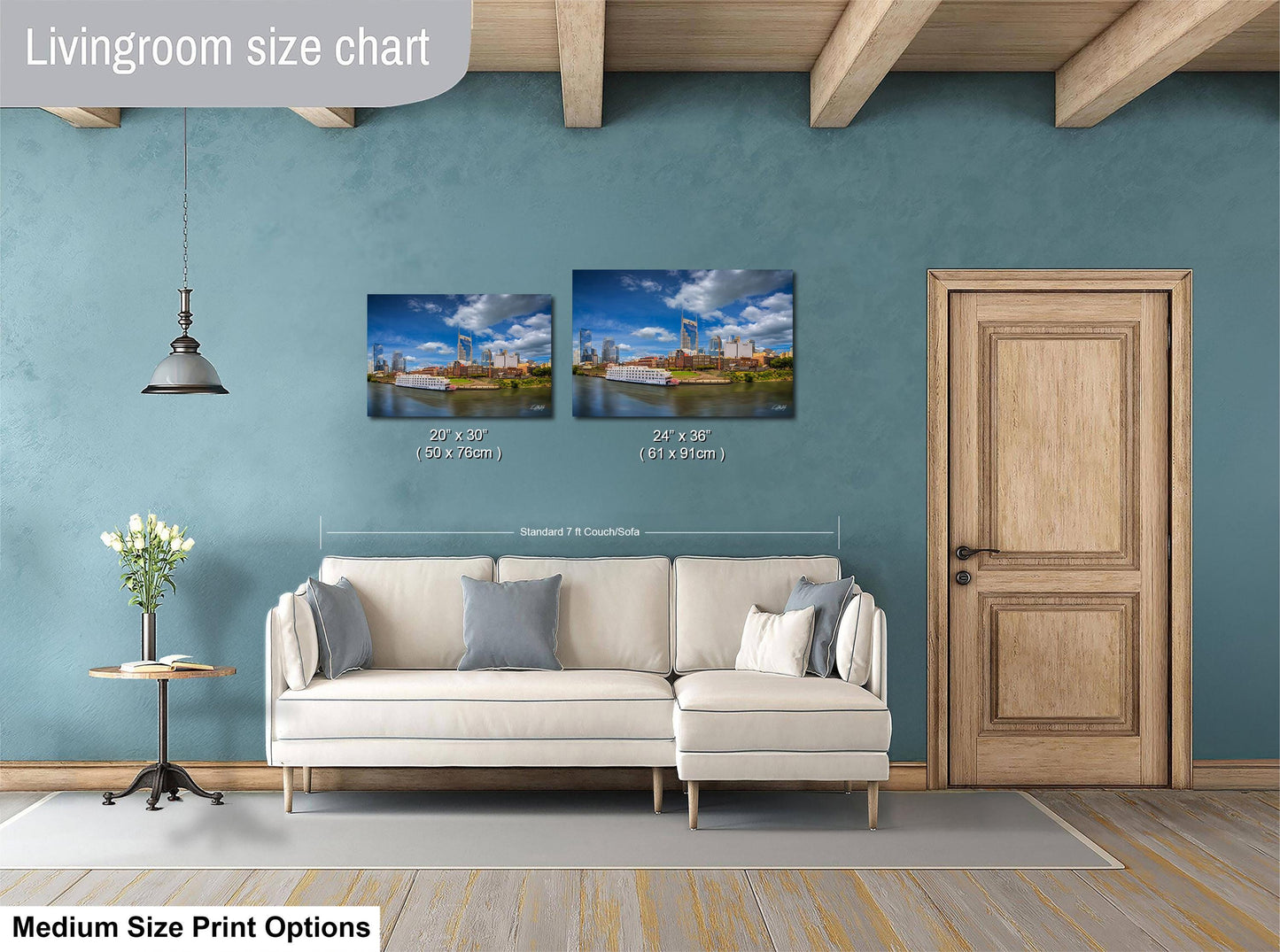 a living room with a white sofa, a wooden door, and a hanging light fixture. Above the sofa, there is a size chart for a medium-sized print, indicating the dimensions of the print in both inches and centimeters.