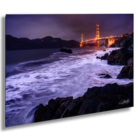 a serene night scene of the Golden Gate Bridge, with its iconic towers illuminated against the dark sky and the waves crashing against the rocky shoreline.