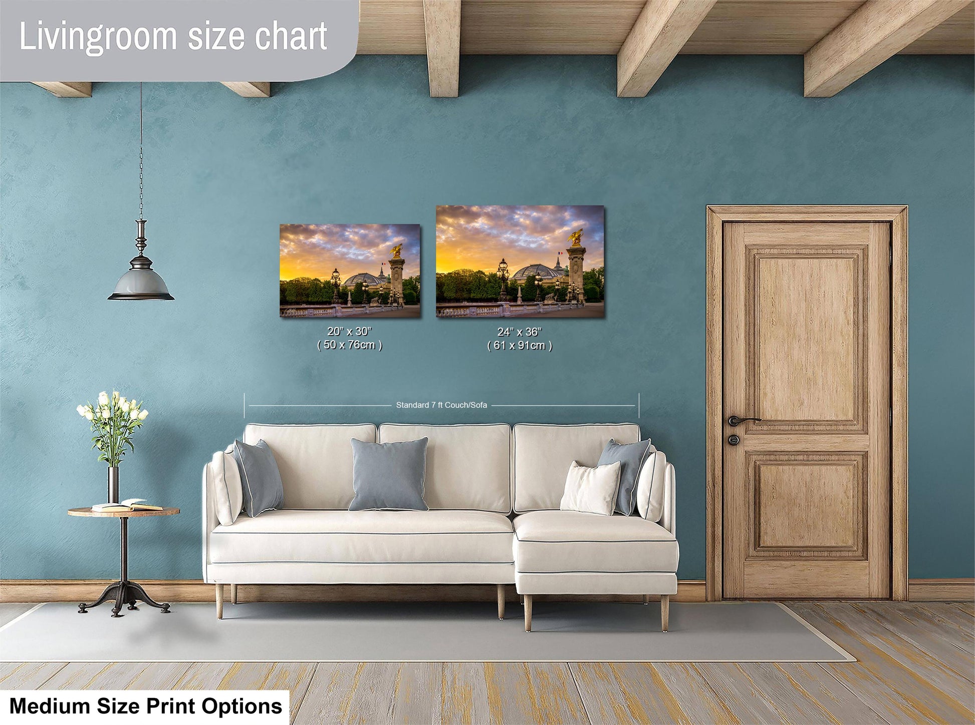 a living room with a white sofa, a wooden door, and a painting of a sunset on the wall. The painting is of a building with a tower. The living room appears to be well-lit and decorated with a vase of flowers on a table.