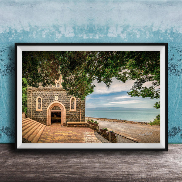 A framed photograph depicting a stone building with arched windows and a stone walkway leading to a beach with a blue sky and trees in the background.
