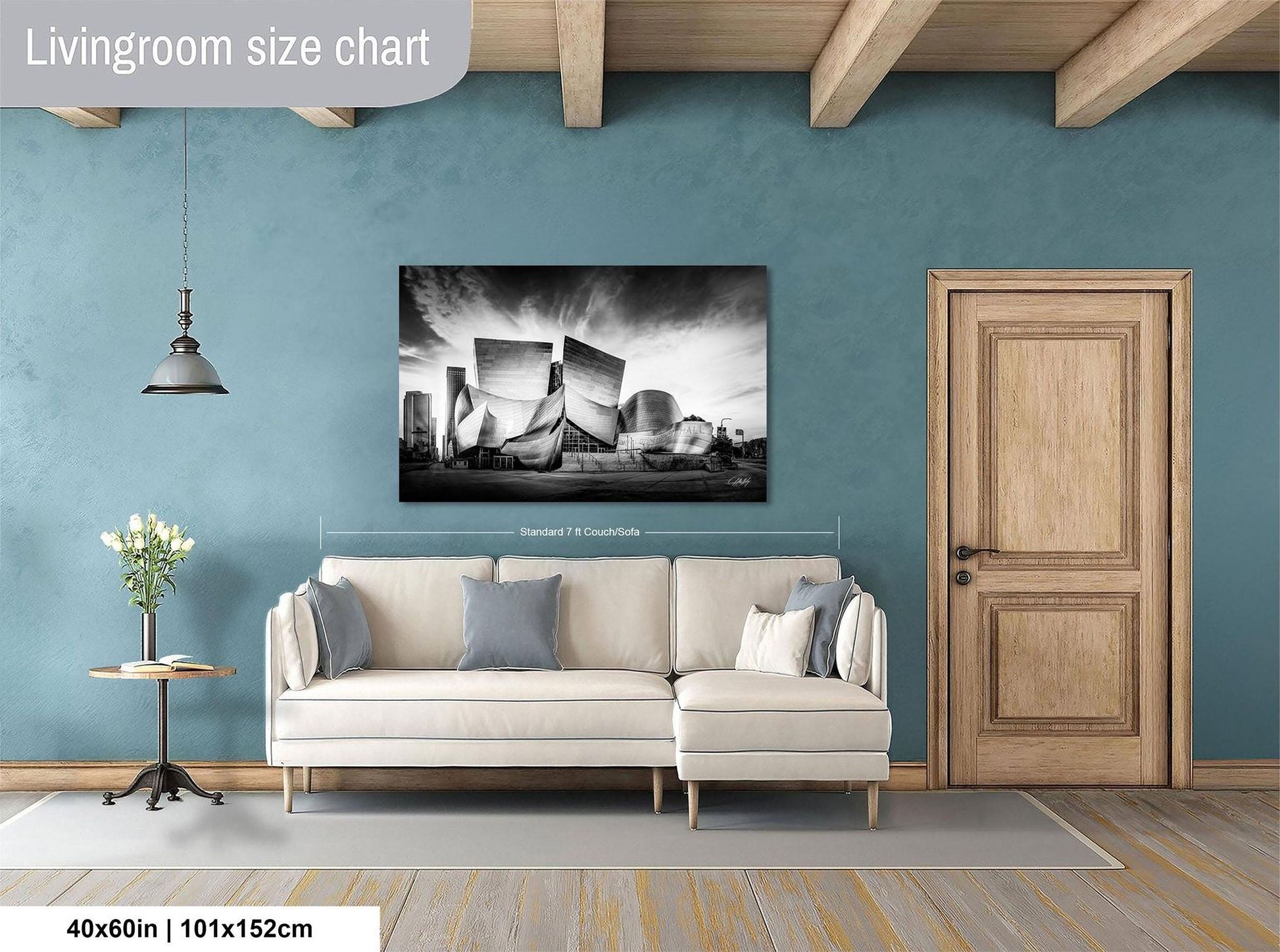 a living room with a large white sofa, a wooden door, and a framed black and white photograph of a city skyline hanging on the wall.