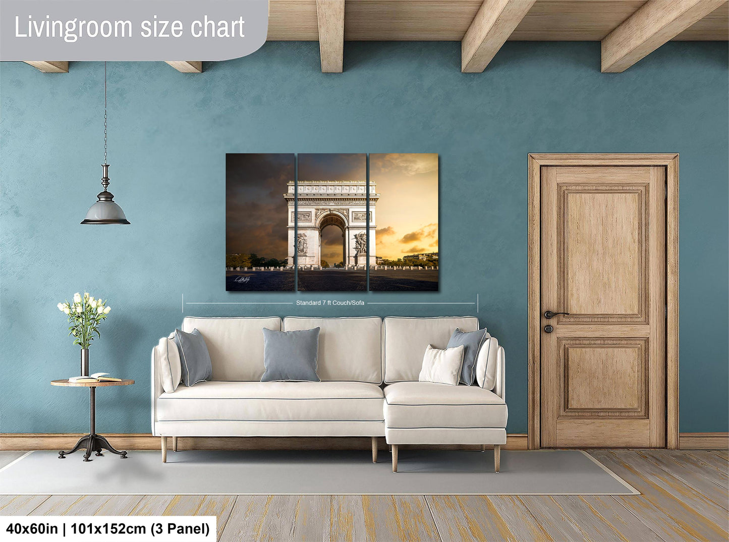The image is a living room with a large white sofa, a wooden door, and a wall with a large painting depicting the Arc de Triomphe in Paris.