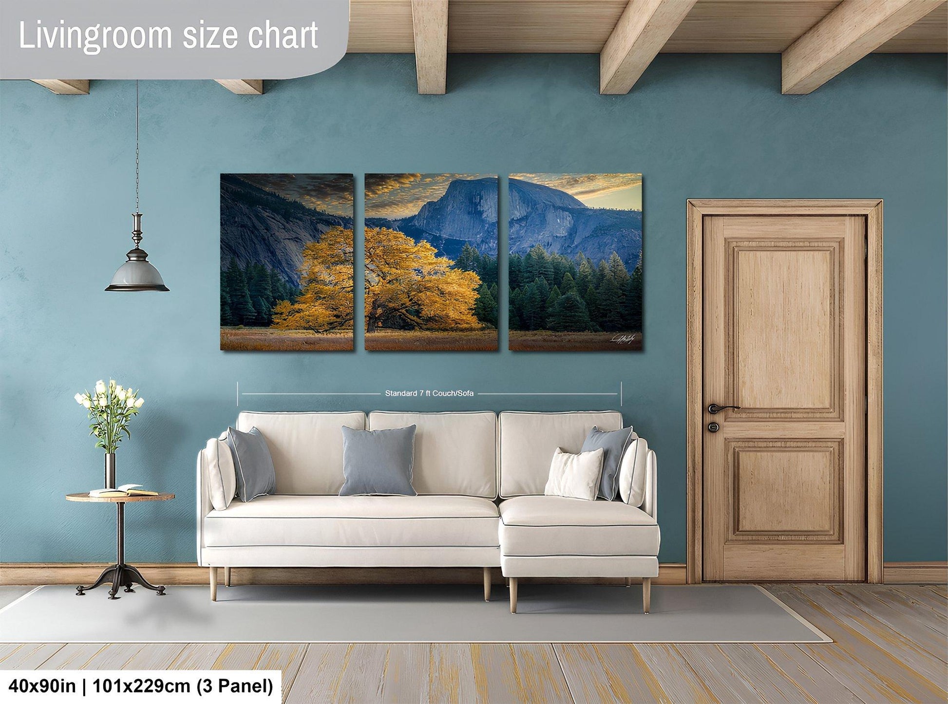 The image is a living room with a large white sofa, a wooden door, and a painting of a mountain landscape hanging on the wall.