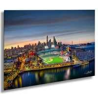 A vibrant nighttime view of a baseball stadium, with the city skyline and bridges in the background illuminated by colorful lights.