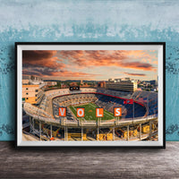 A framed photograph of a sports stadium with the word "VOLS" prominently displayed, set against a backdrop of a colorful sunset sky.