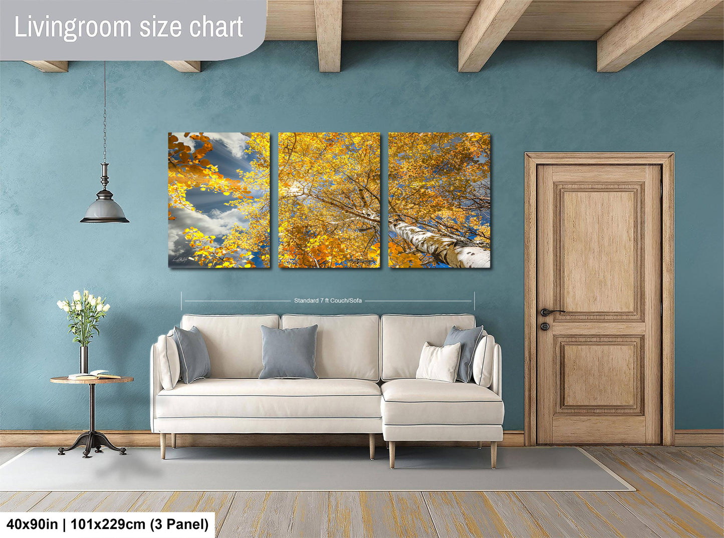 The image is a living room with a white sofa and a wooden door. Above the sofa, there is a large wall art depicting a tree with yellow leaves. The wall art is divided into three panels, each showing different parts of the tree. The living room has a blue wall and a wooden floor.