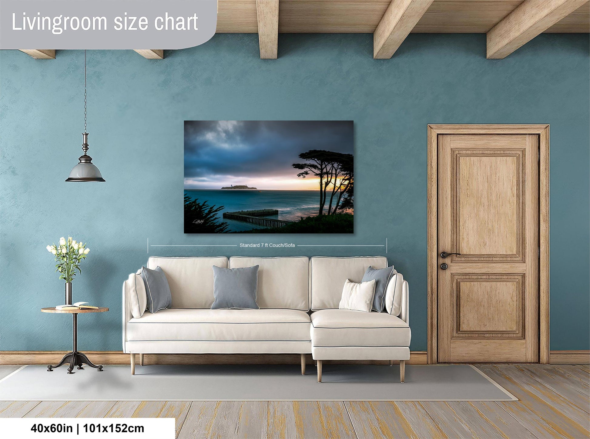 a living room with a large painting of a serene landscape hanging on the wall. The painting features a tranquil scene of a body of water, possibly a lake or ocean, with a sunset in the background. The room is furnished with a white sofa and a wooden door, creating a cozy and inviting atmosphere.