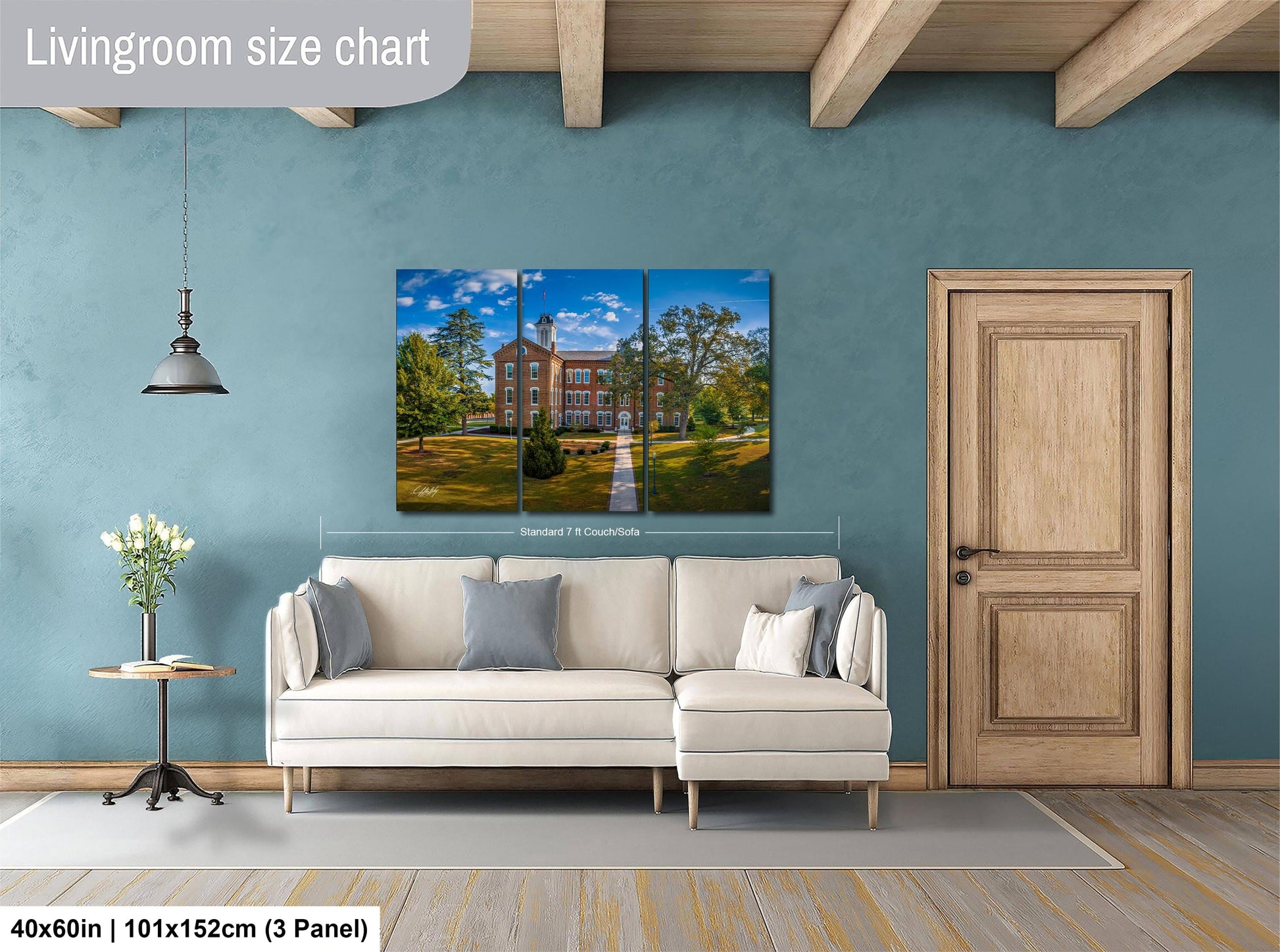 The image is a living room with a large white sofa, a wooden door, and a painting of a building on the wall.