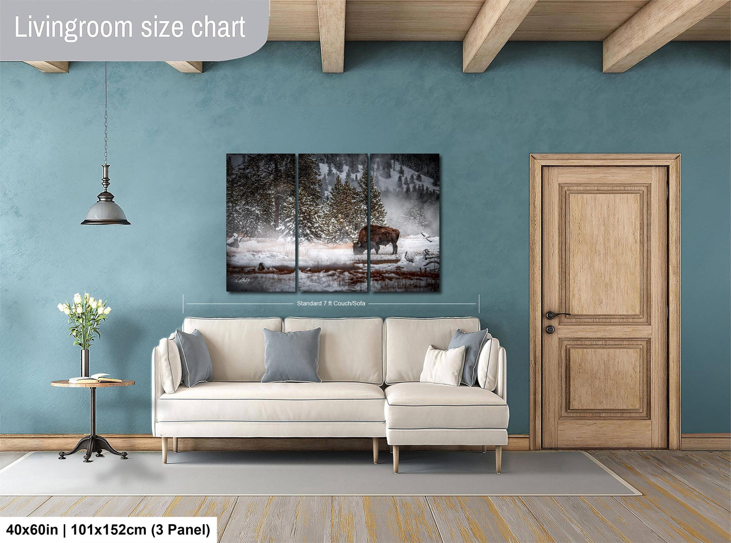 The image is a living room with a large white sofa, a wooden door, and a painting of a moose in a snowy forest on the wall.
