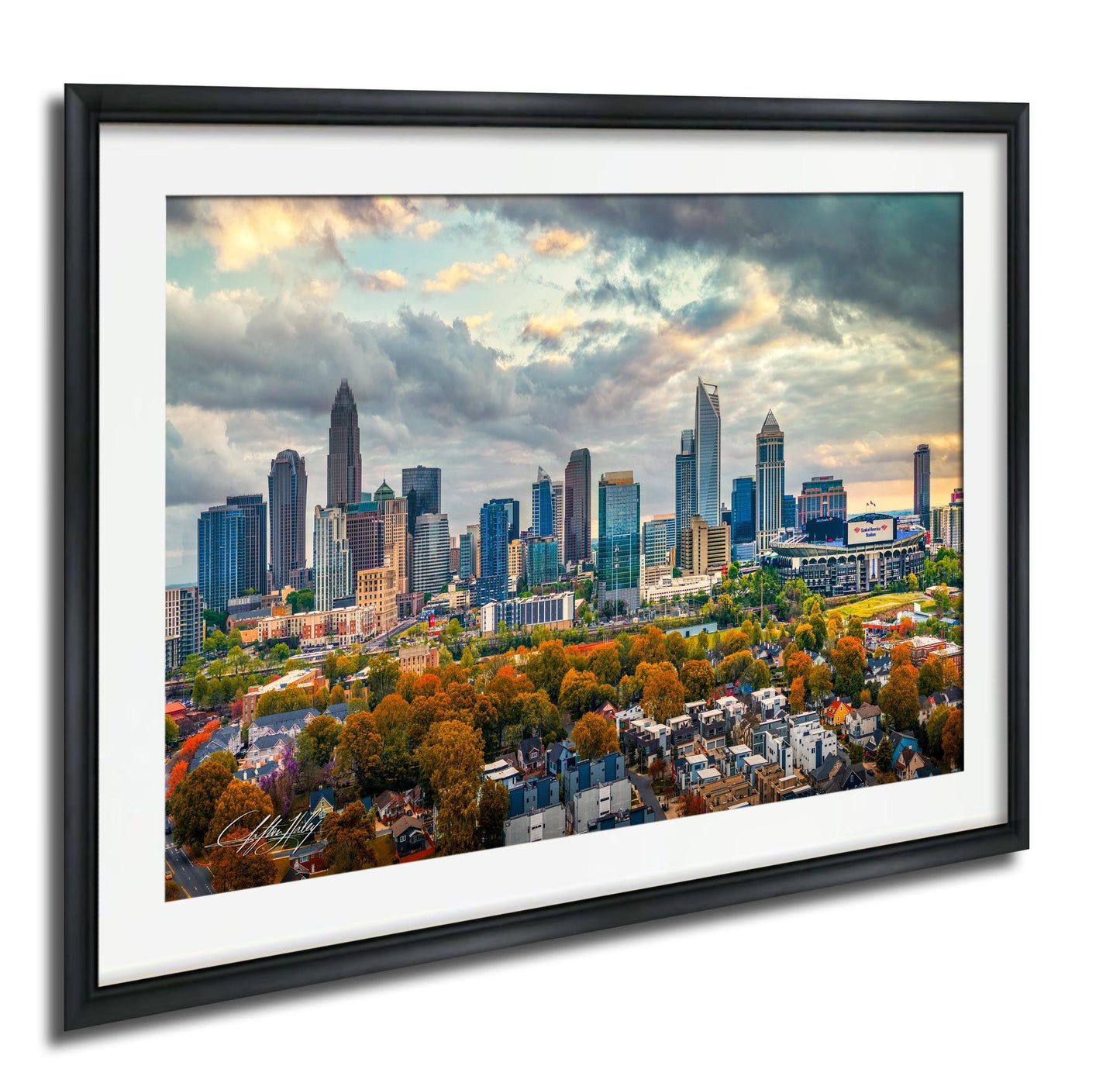 a cityscape with tall buildings and skyscrapers, surrounded by trees with autumn foliage. The sky is cloudy, creating a dramatic backdrop for the city skyline.
