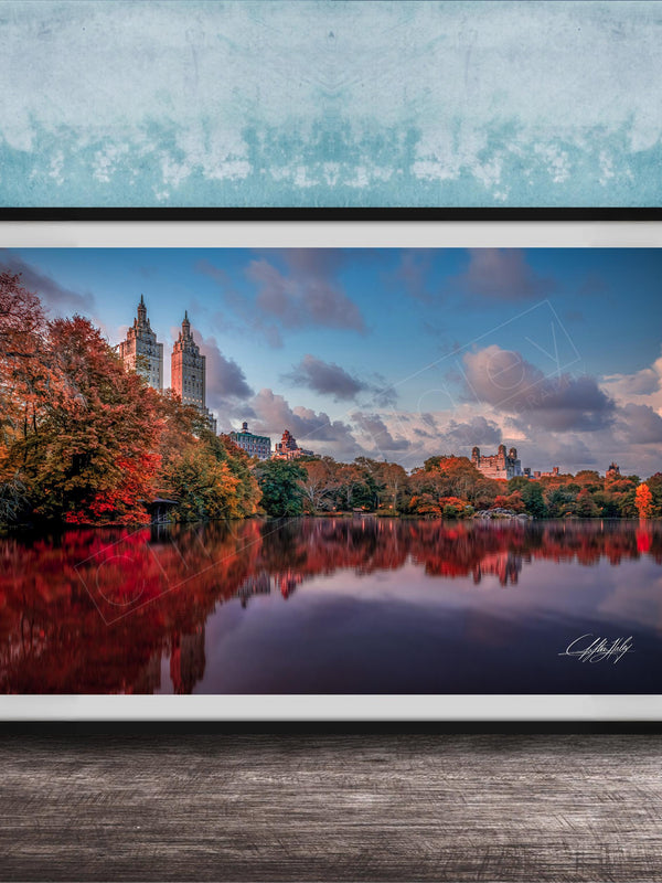 A framed photograph of the New York City skyline, with the city's iconic landmarks and trees reflected in the water below.
