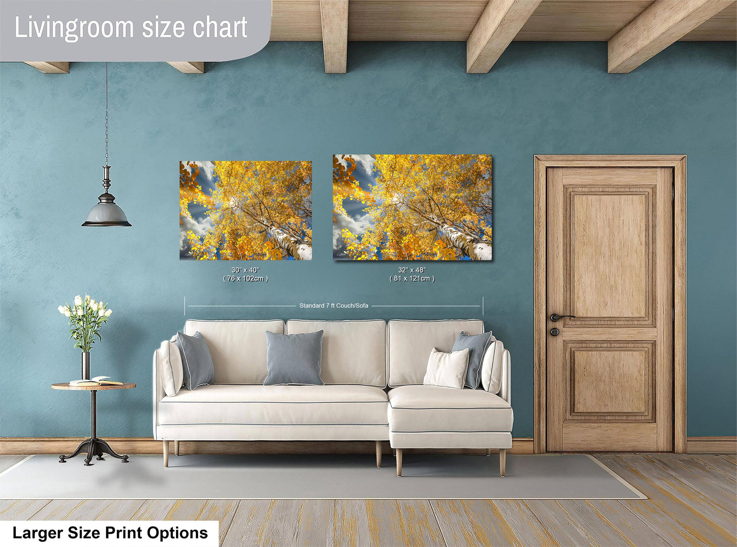 a living room with a white sofa, a wooden door, and two framed pictures of a tree with yellow leaves hanging on the wall.