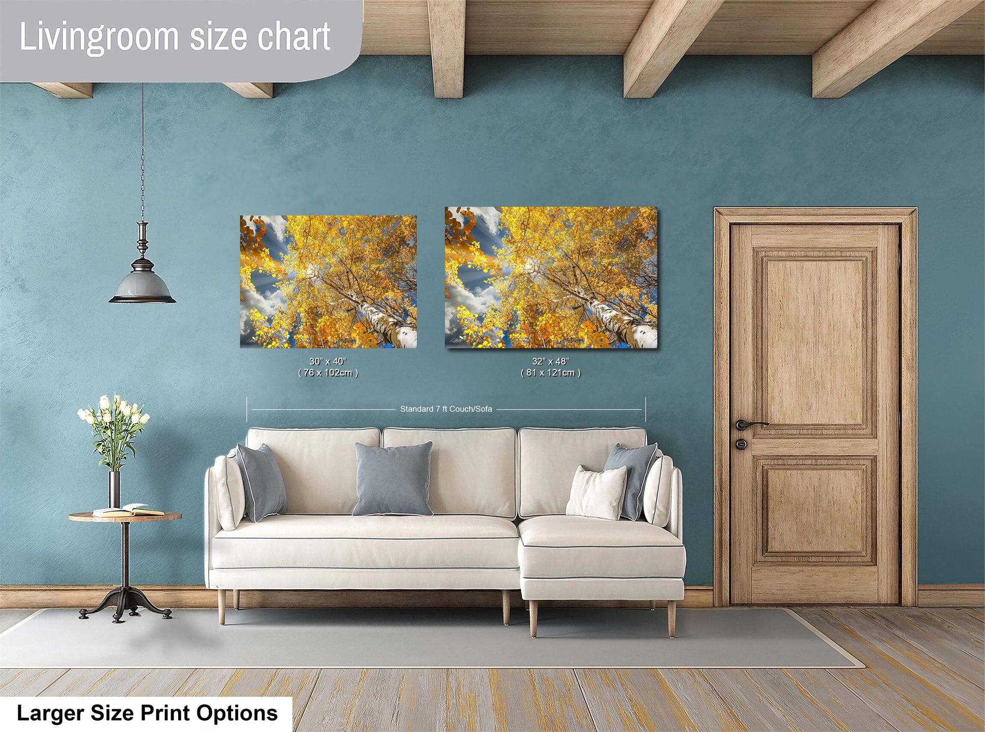 a living room with a white sofa, a wooden door, and two framed pictures of a tree with yellow leaves hanging on the wall.