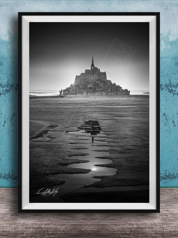 A black and white photograph of a castle or palace situated on a beach, with a body of water in the foreground and a sky above.