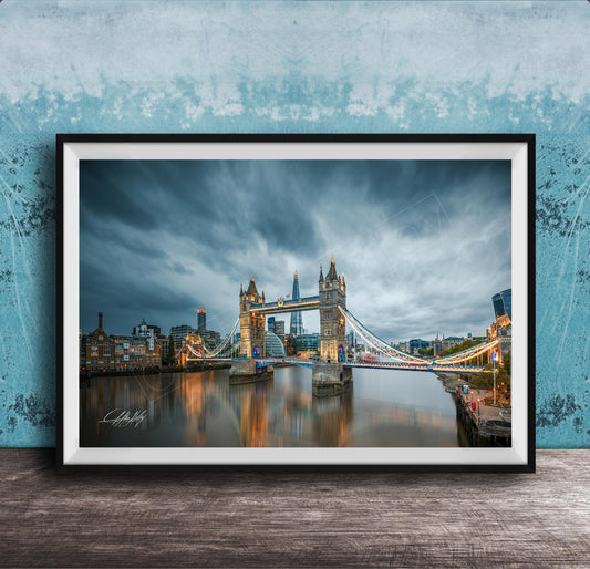 A framed photograph of the iconic Tower Bridge in London, England, with the bridge illuminated against a cloudy sky.