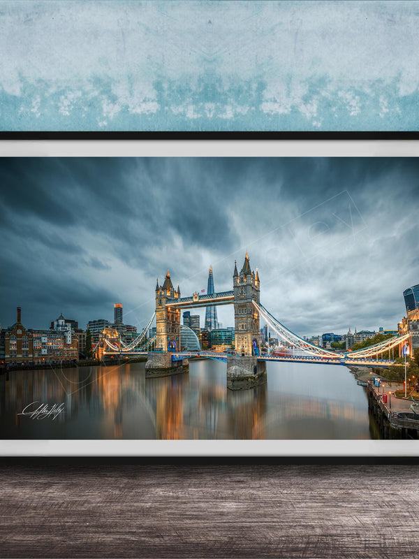 A framed photograph of the iconic Tower Bridge in London, England, with the bridge illuminated against a cloudy sky.
