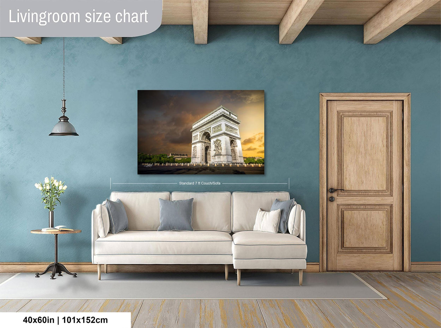 a living room with a large white sofa, a wooden door, and a painting of the Arc de Triomphe hanging on the wall.
