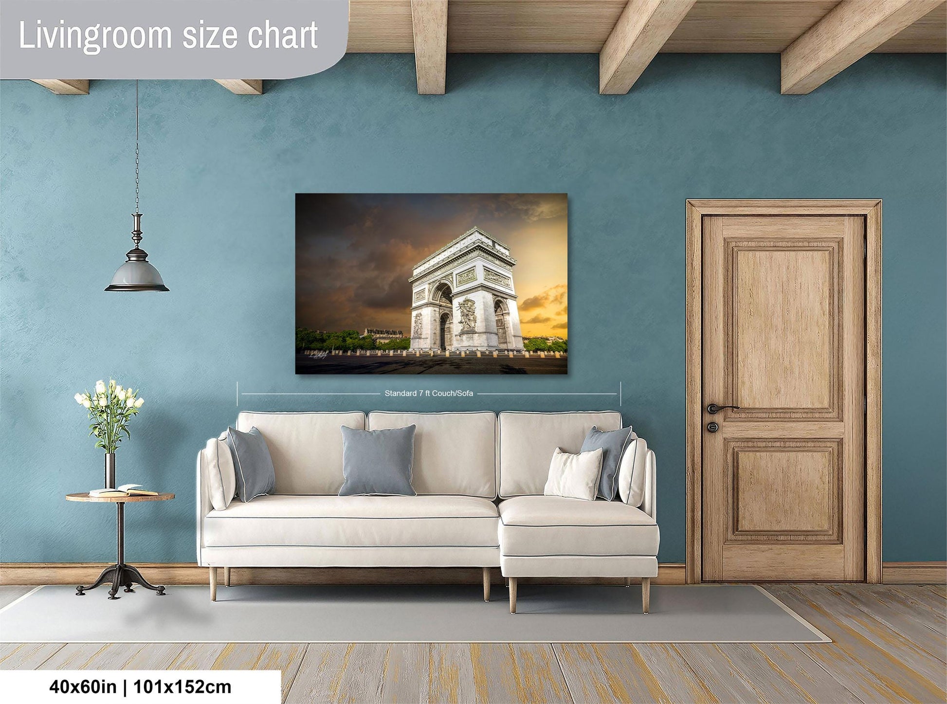 a living room with a large white sofa, a wooden door, and a painting of the Arc de Triomphe hanging on the wall.