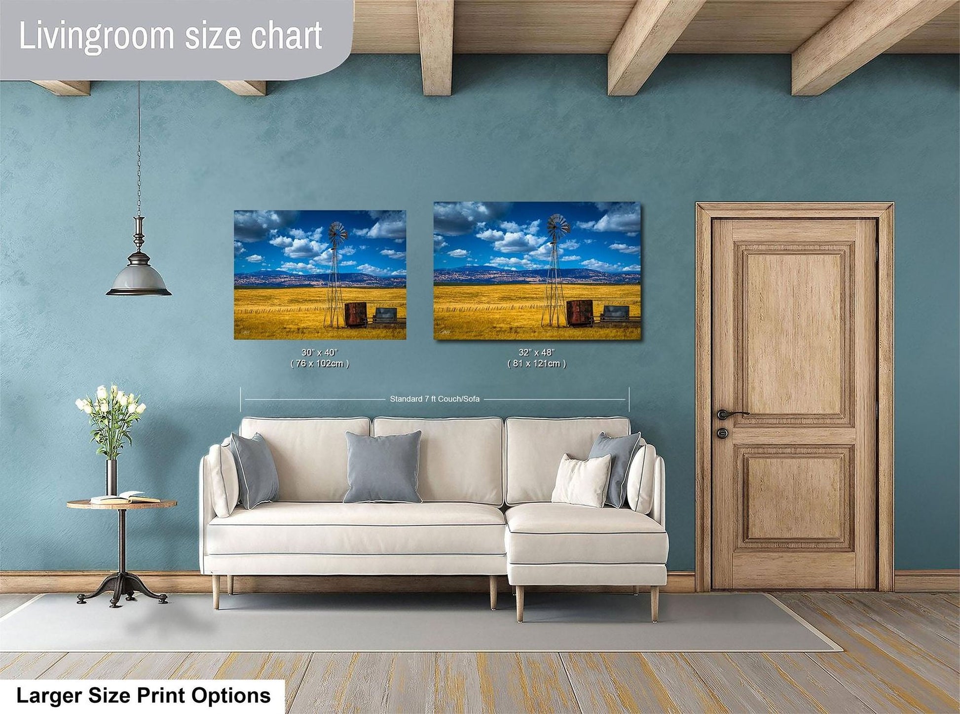 a living room with a white sofa, a wooden door, and two framed pictures of a windmill and a field on the wall.