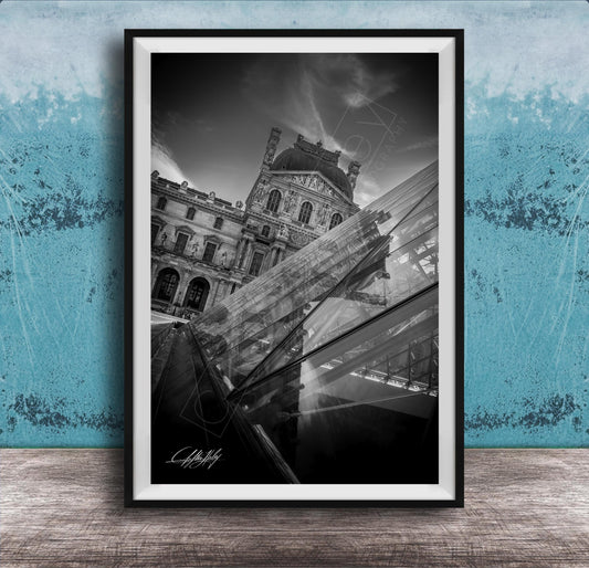 A black and white photograph of the Louvre Museum in Paris, France, with a modern glass structure in the foreground.