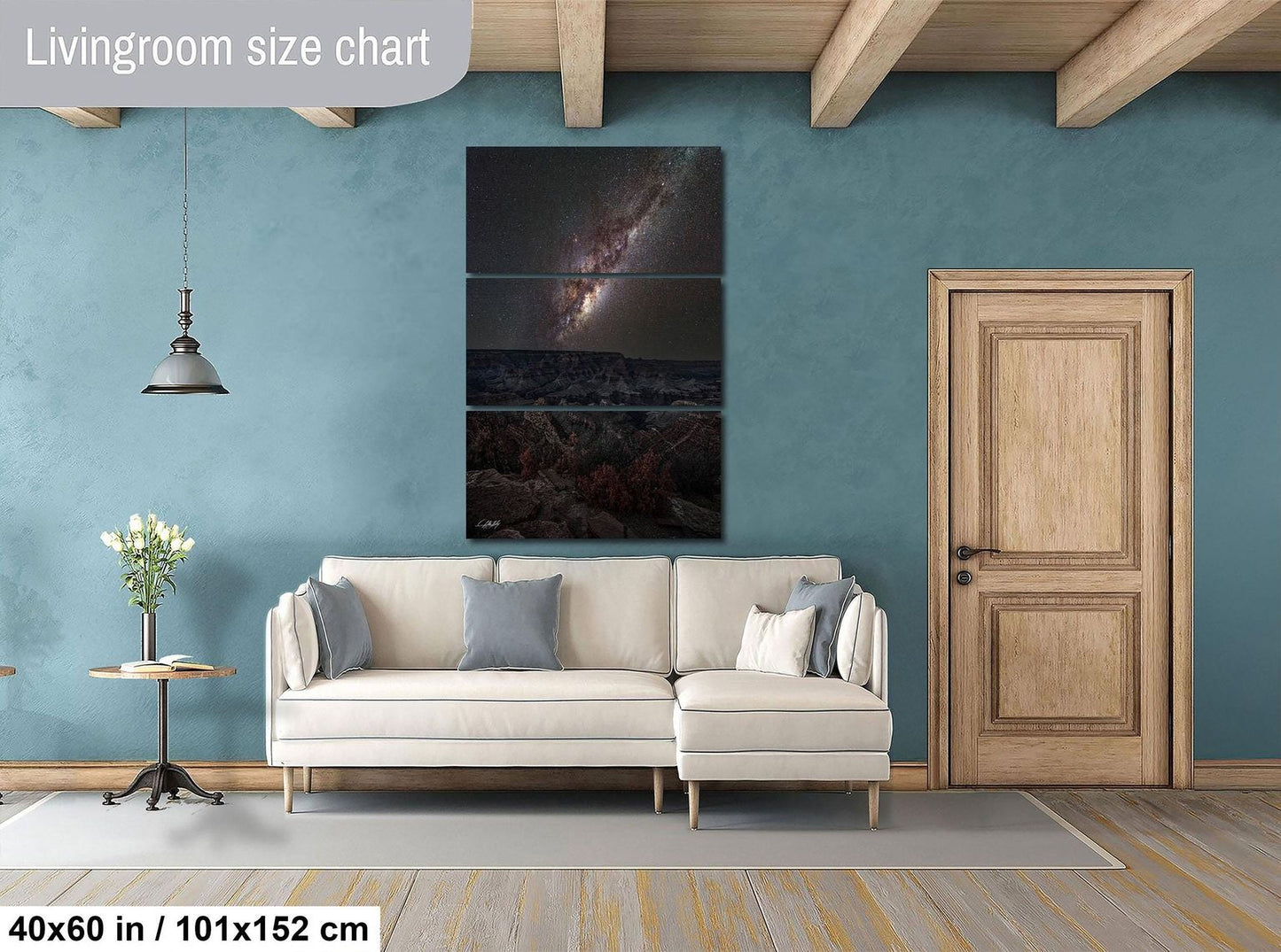 The image is a living room with a large white sofa, a wooden door, and a painting of a galaxy hanging on the wall.