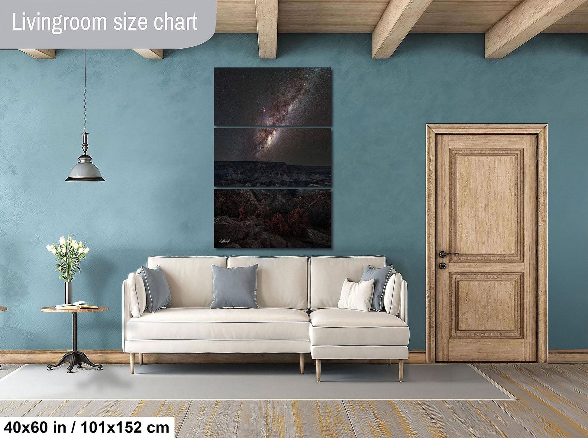 The image is a living room with a large white sofa, a wooden door, and a painting of a galaxy hanging on the wall.