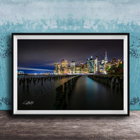 A framed photograph of the New York City skyline at night, with the city's iconic skyscrapers and landmarks illuminated against a dark sky.