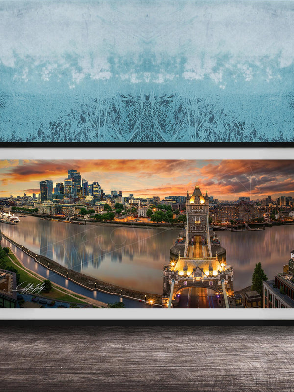 A framed photograph of the skyline of a city at sunset, with the city's iconic landmarks and buildings illuminated against a colorful sky.