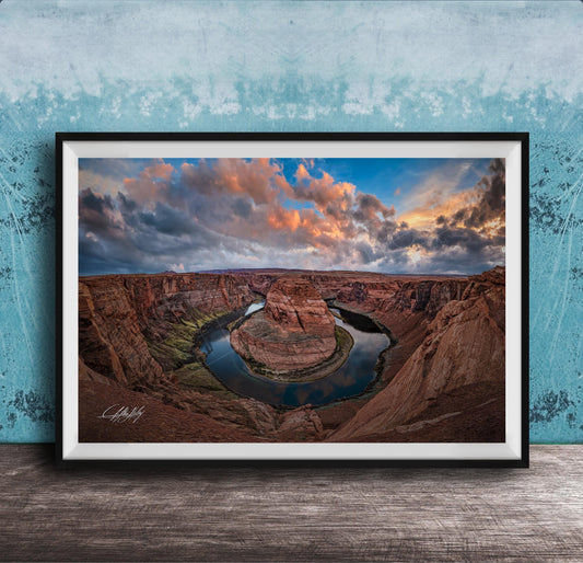A framed photograph of the Grand Canyon, showcasing the stunning natural landscape with a winding river and dramatic clouds in the sky.