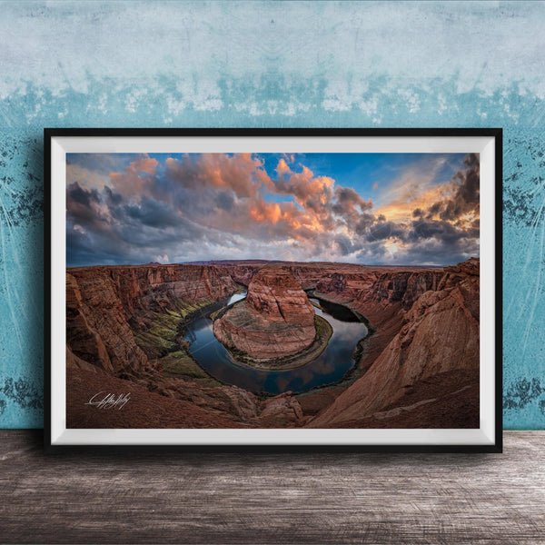 A framed photograph of the Grand Canyon, showcasing the stunning natural landscape with a winding river and dramatic clouds in the sky.