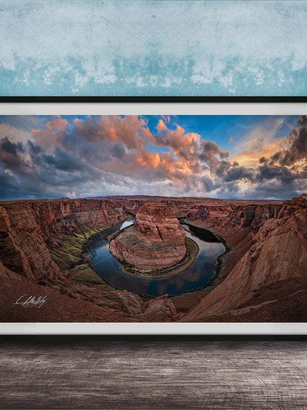 A framed photograph of the Grand Canyon, showcasing the stunning natural landscape with a winding river and dramatic clouds in the sky.