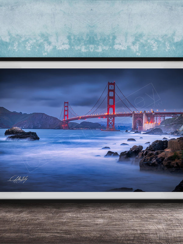 A framed photograph of the Golden Gate Bridge at night, with the bridge illuminated against a dark sky and the ocean in the foreground.